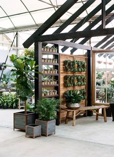 the inside of a greenhouse with potted plants on shelves and tables in front of it