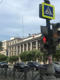 a traffic light sitting on the side of a road next to a tall white building