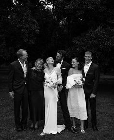 a group of people standing next to each other on a field with trees in the background