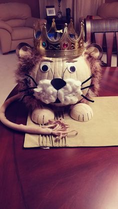 a lion with a crown on top of it's head sitting on a table