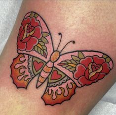 a colorful butterfly tattoo with roses on it's back leg and the word love is written in black ink