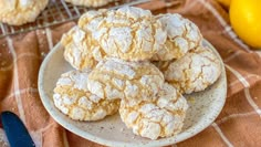 a plate full of powdered sugar cookies next to some lemons and a knife