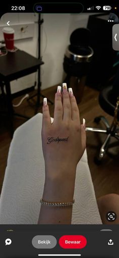 a person's hand with a small tattoo on their left wrist and the other hand is