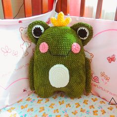 a crocheted frog pillow with a crown on it's head and eyes