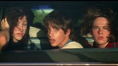 three people sitting in the back seat of a car