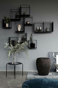 a living room with grey walls and black shelvings on the wall above a blue ottoman