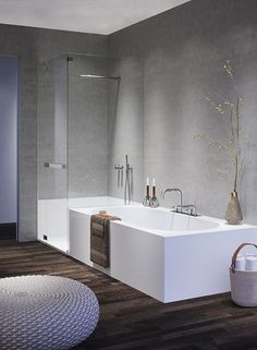 a large white bath tub sitting on top of a wooden floor next to a shower