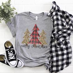 a t - shirt that says merry christmas on it next to some shoes and a plant