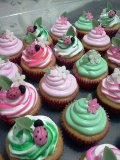 many cupcakes are decorated with pink, green and white frosting