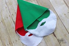 a green and red elf hat on top of a wooden floor