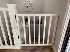 there is a clock on the wall next to a white stair railing in this house