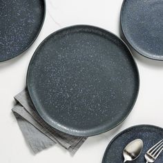 three black plates with forks and spoons sitting on top of each other next to napkins