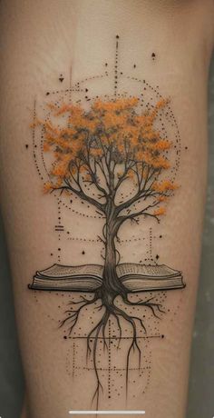 a tree with orange leaves on the side of a woman's thigh and an open book