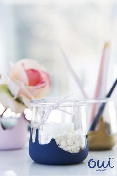 there is a small jar with marshmallows in it next to some pens and pencils