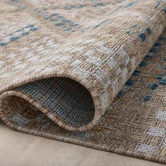 a rug with blue and beige designs on the bottom is laying on top of a couch