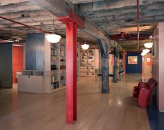 an empty library with red chairs and bookshelves in the center, surrounded by wooden flooring