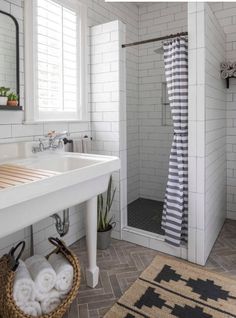 a white tiled bathroom with a shower, sink and mirror