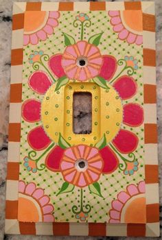 a decorative light switch cover with flowers and stripes on the bottom, painted in bright colors