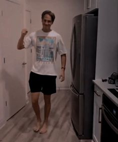 a man standing in a kitchen next to a refrigerator