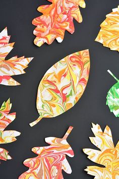 colorful paper leaves are arranged on a black surface