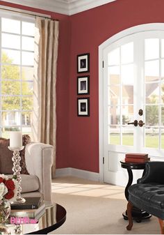 a living room with red walls and white trim on the doors, windows, and chairs