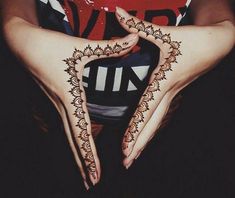 a woman's hands with henna tattoos on them