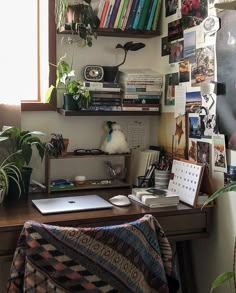 a desk with books, plants and pictures on the wall above it is also a laptop