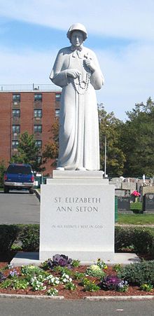 a large statue in the middle of a flower bed