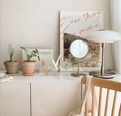 a desk with a lamp, mirror and other items on it