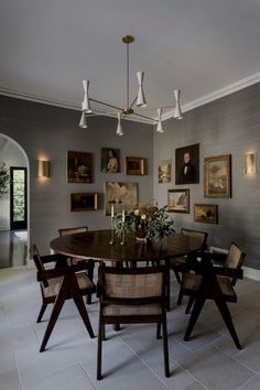 a dining room table with chairs and pictures on the wall behind it, along with candles