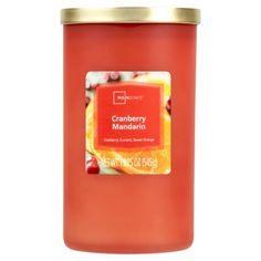 a red candle that is sitting on a white surface and has a label reading cranberry mandarin