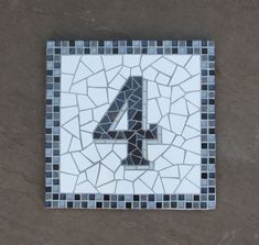 the number four is made out of mosaic tiles and has been placed in front of a wall