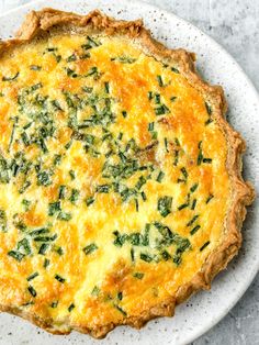 a quiche with spinach and cheese on a white plate