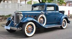 an old blue car is parked on the street