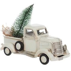 an old white truck with a christmas tree in the back and basket on the bed