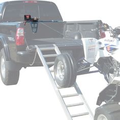 a black truck pulling a motorcycle on the back of it's flatbed and ramp