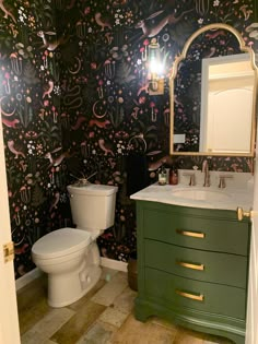 a bathroom with a green vanity, toilet and sink in it's own room