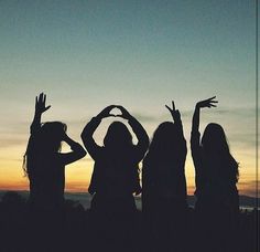 three girls are standing in front of the sunset with their hands up and arms raised