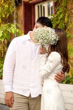 a man and woman are kissing in front of a house with flowers on their forehead