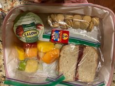 a lunch bag filled with sandwiches, fruit and crackers on top of a counter