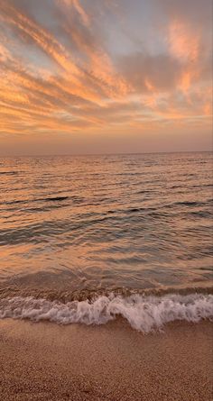 the ocean waves come in to shore as the sun goes down over the water and clouds