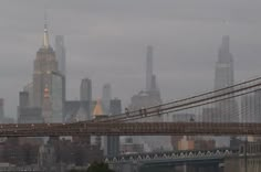 an airplane is flying over the brooklyn bridge in new york city, ny on a foggy day