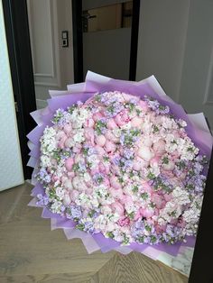 a large bouquet of pink and white flowers on top of a purple paper wrapper