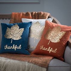 three decorative pillows on a couch with the words, thank you thanks and leaves printed on them