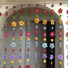 colorful paper flowers hanging from the side of a doorway with an open door in the background