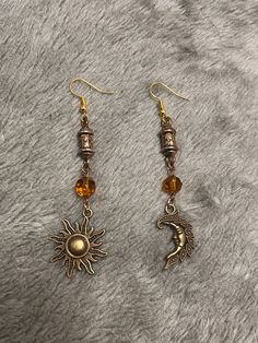 Dangle bronze earrings with a sun and moon charm. Hook is made from hypoallergenic gold plated alloy. Sun Aesthetic Jewelry, Sun Gold Earrings, Gold Moon Phase Symbolic Earrings, Gold Symbolic Moon Phase Earrings, Symbolic Metal Earrings With Moon Charm, Symbolic Moon Charm Earrings, Gold Dangle Earrings With Sun And Moon Design, Brass Sun And Moon Drop Earrings, Bronze Metal Jewelry With Moon Charm