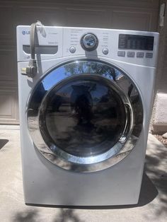 a washing machine sitting in front of a garage door with its reflection on the window