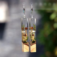 the earrings are made out of glass and have tiny plants in them, as well as mushrooms