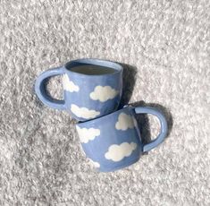 two coffee mugs sitting on top of a carpeted floor next to each other