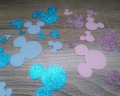 mickey mouse cut outs on a table with glitter and blue, pink and white shapes